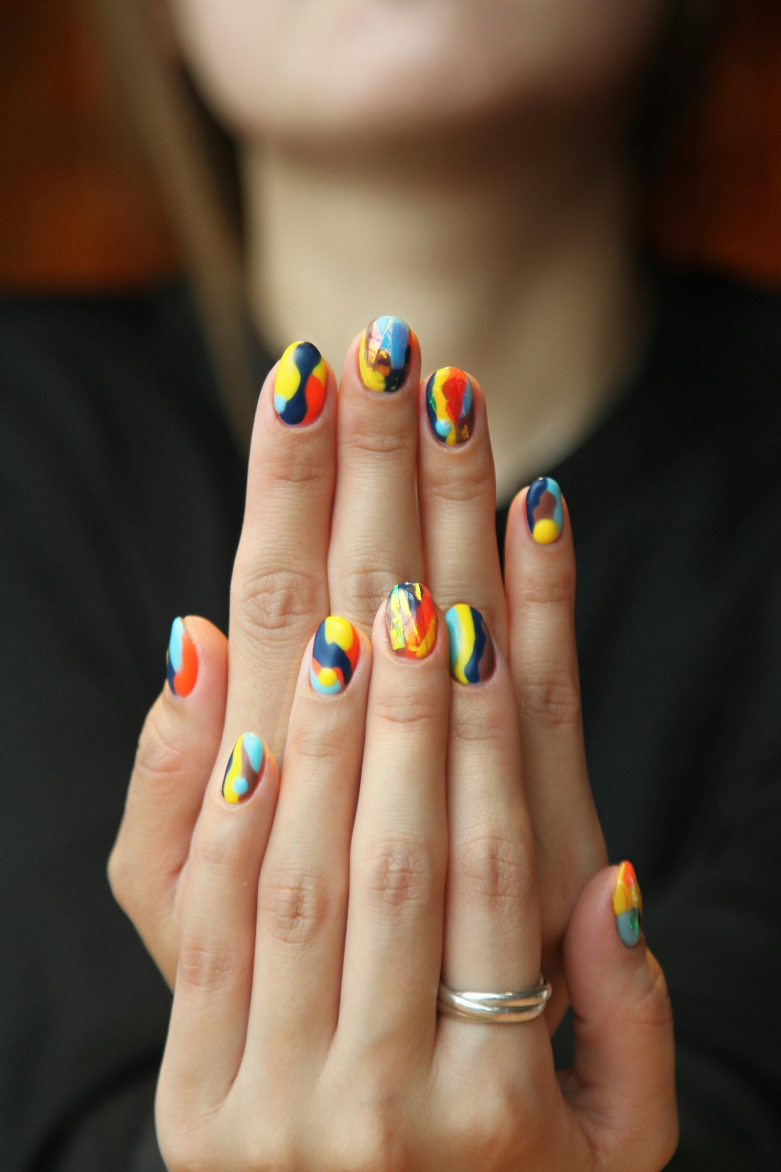 Uñas con un diseño artístico en colores azul, rojo y dorado